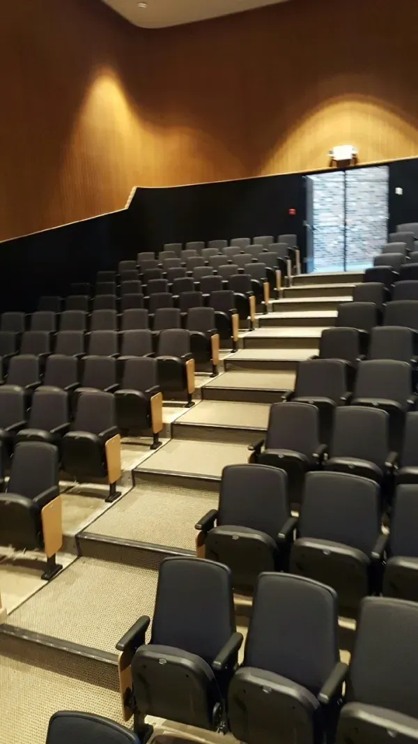 Empty auditorium with rows of black seats.