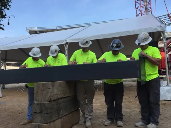 Construction workers signing a steel beam.