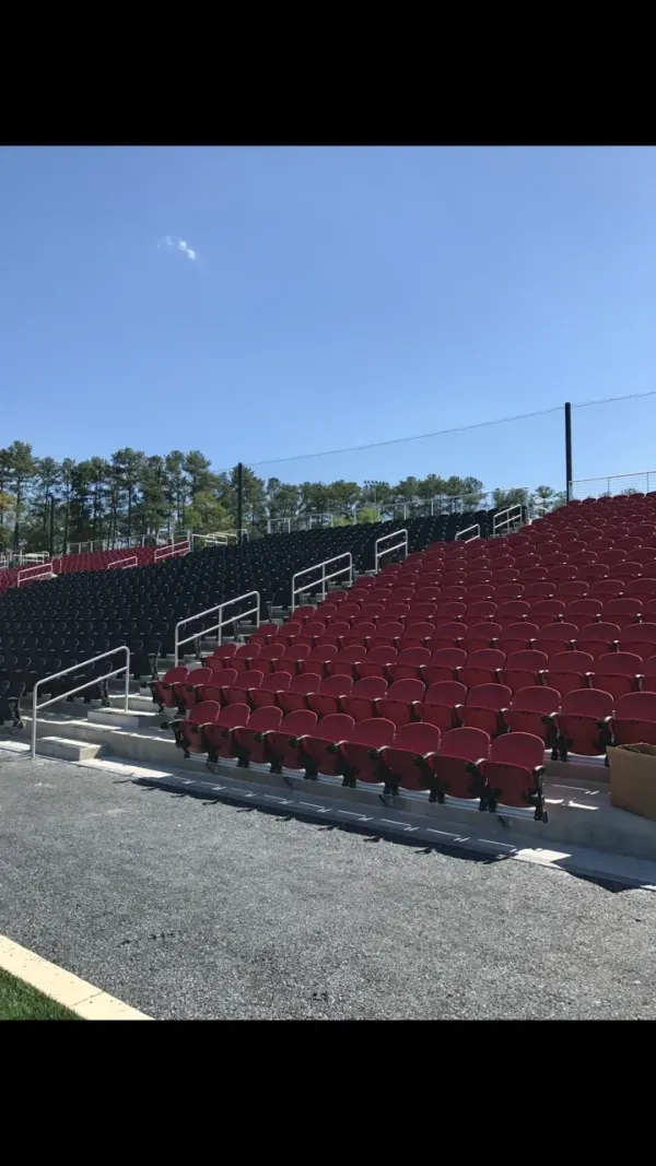 Red and black stadium seats under sky.