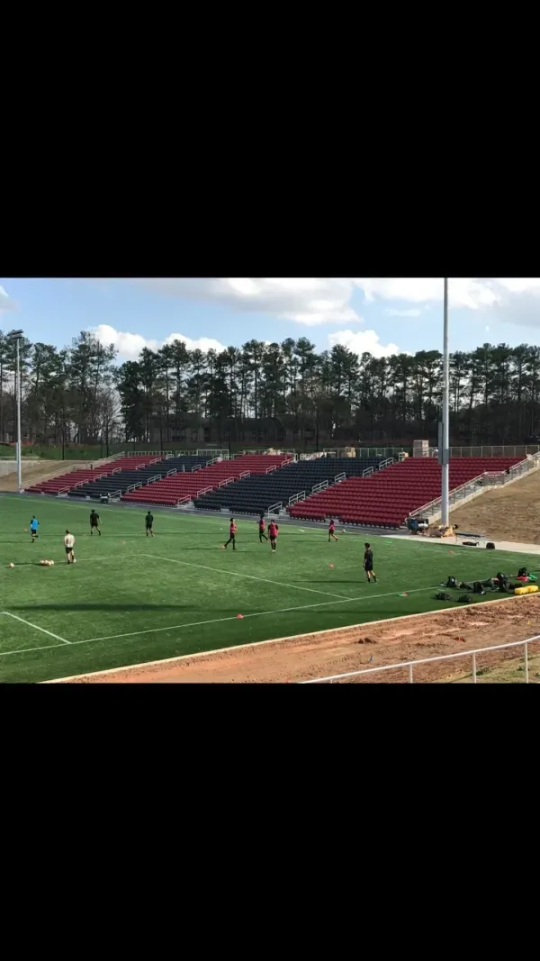 Soccer practice on green field, red bleachers.